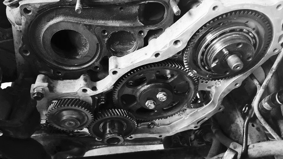 Close up of an engine timing gear train with the cover removed, photographed in black and white