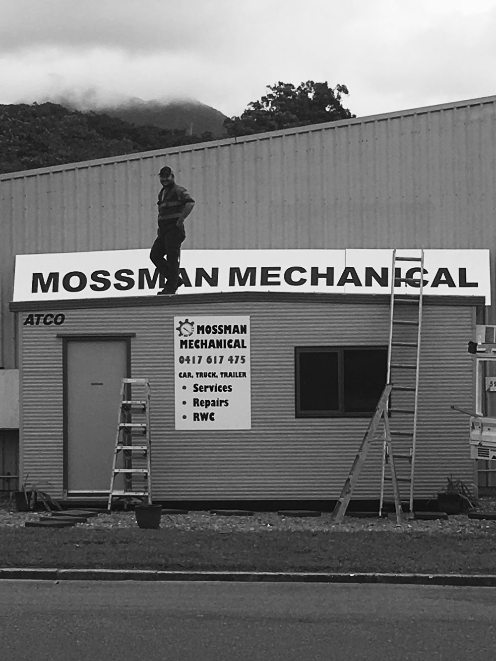 The day the Mossman Mechanical sign went up on the shed roofline, with ladders against the office and the ranges behind