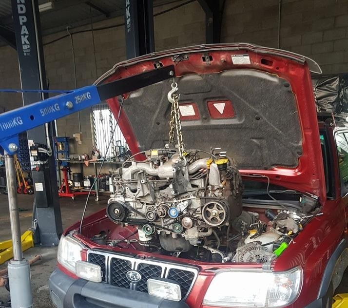 A Subaru Forester with its engine lifted out on an engine crane in the Mossman Mechanical workshop